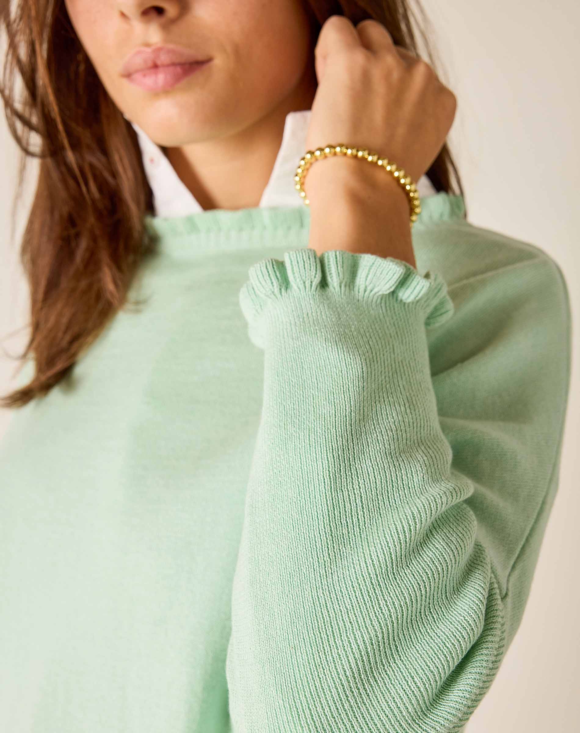 Person wearing a light green sweater with a plain background