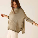 Woman wearing a beige sweater with a plain background
