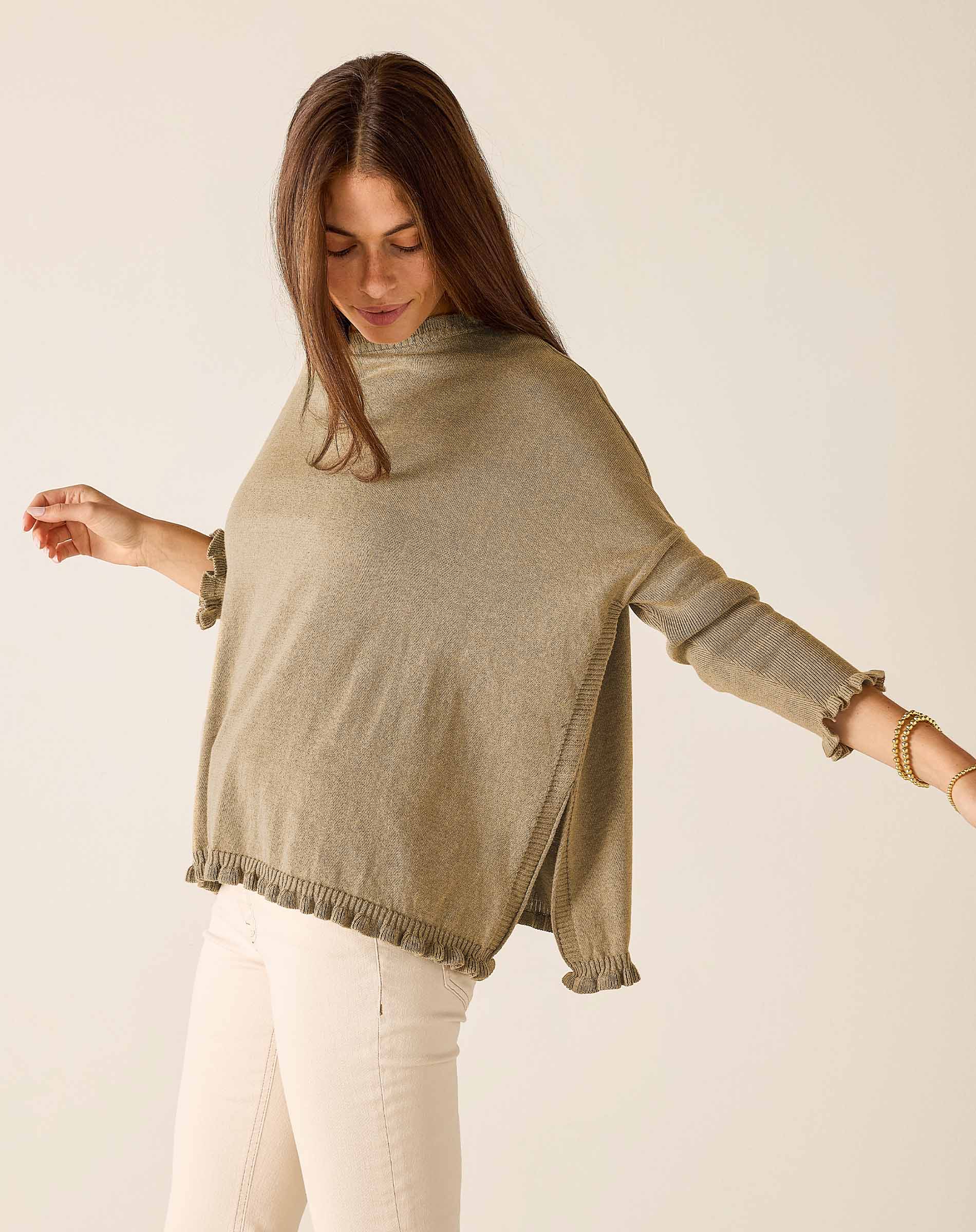 Woman wearing a beige sweater with a plain background