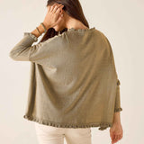 Woman wearing a beige knitted poncho against a plain background