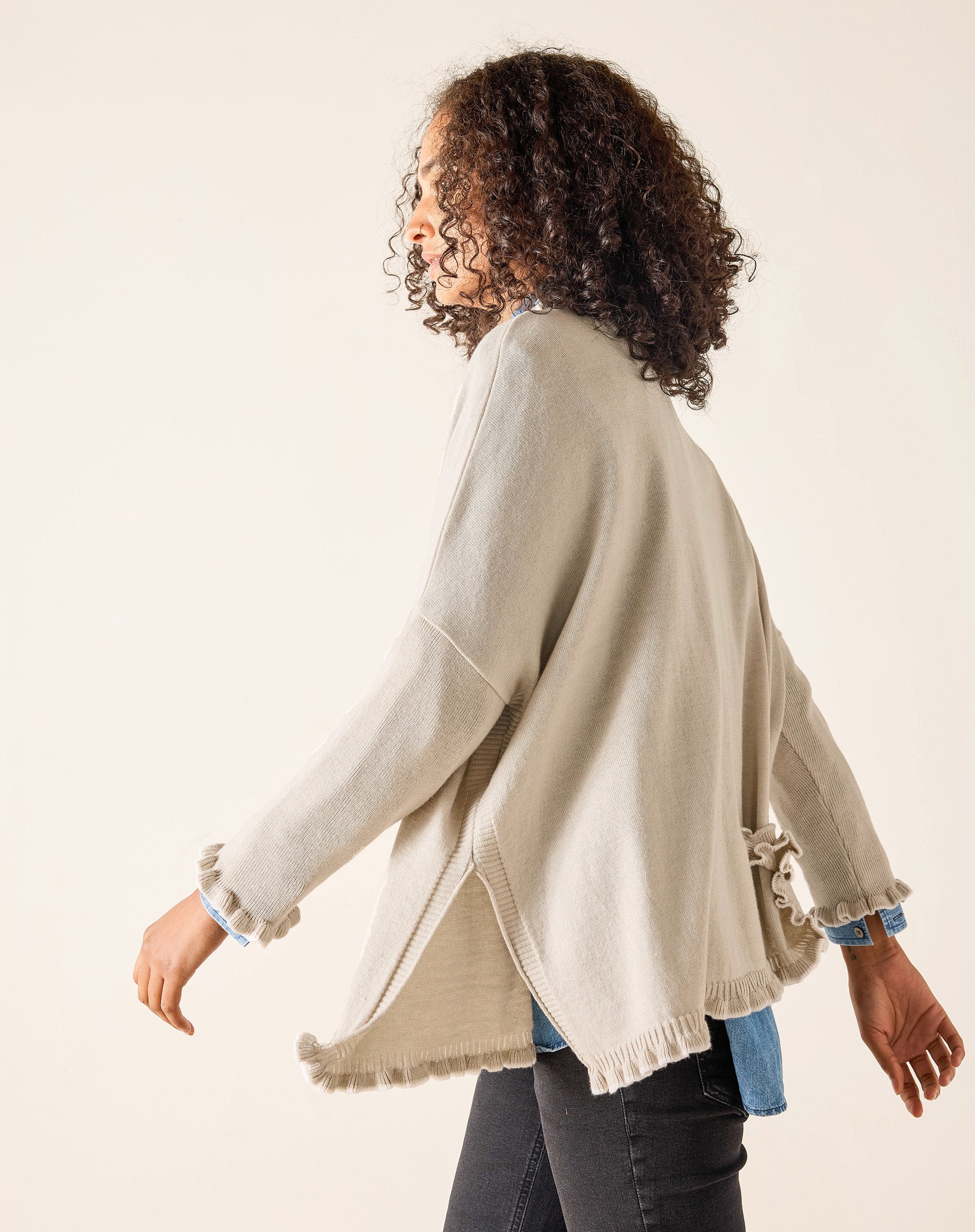 Woman wearing a beige cardigan with a white background
