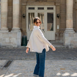 Woman in a white blouse and blue jeans standing in front of a stone building.