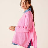 Woman wearing a pink sweater over a denim shirt on a beige background