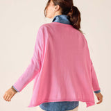 Woman wearing a pink cardigan over a denim shirt on a beige background