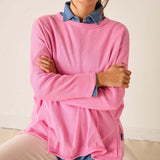 Person wearing a pink sweater with denim collar and cuffs on a neutral background