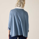 Person wearing a blue sweater with a white collar on a beige background