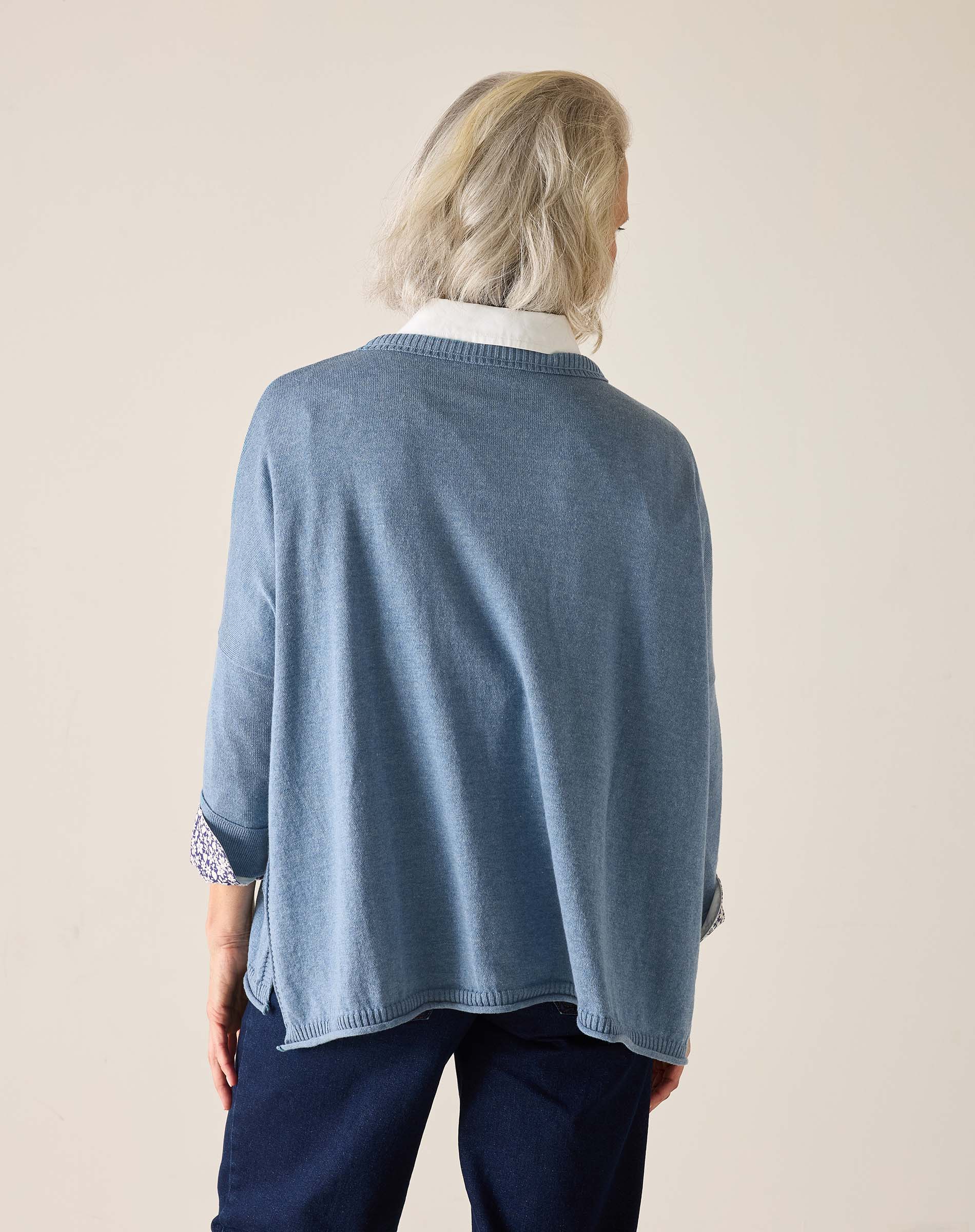 Person wearing a blue sweater with a white collar on a beige background