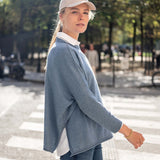 Image of a woman wearing a blue crewneck sweater with side slits