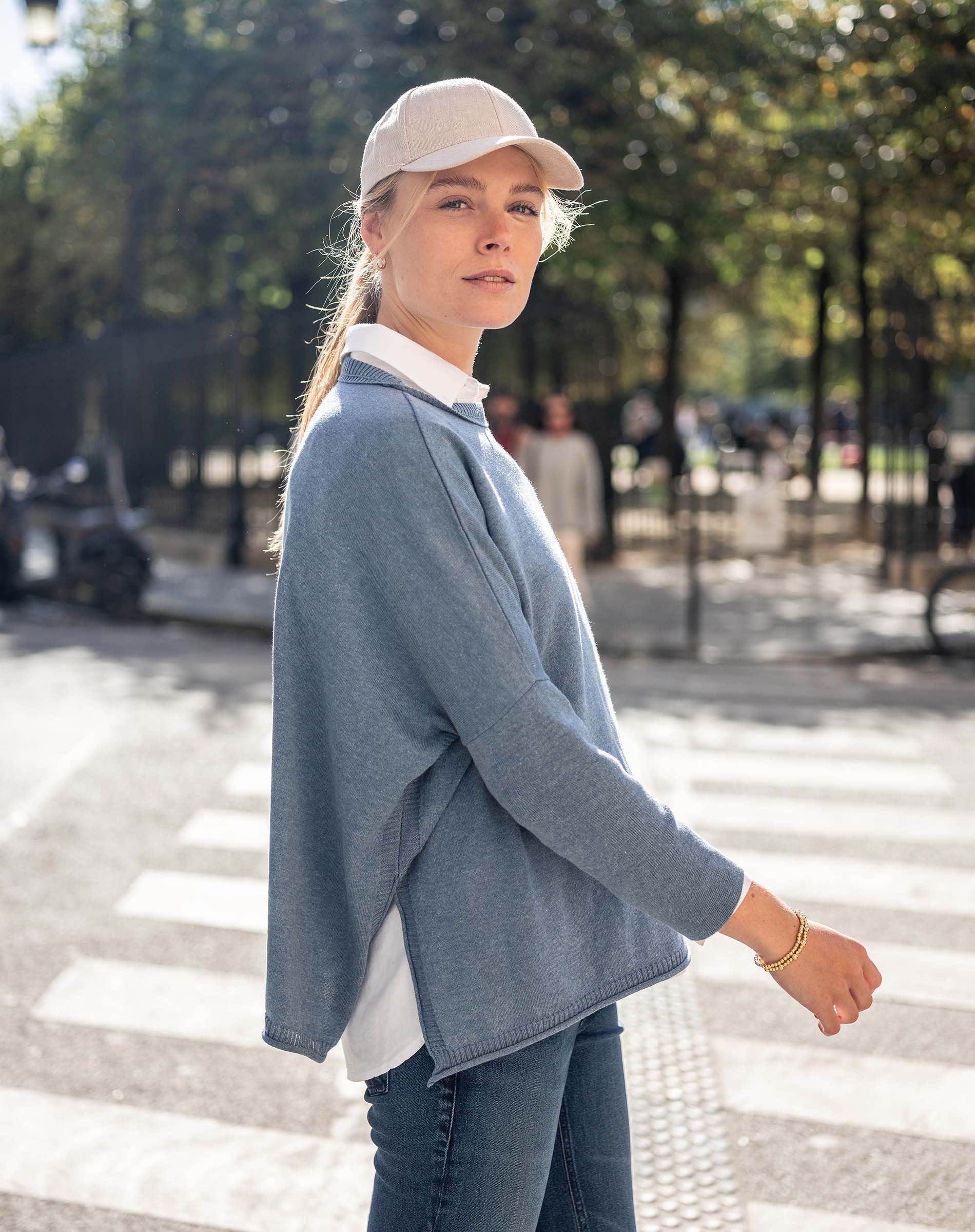 Image of a woman wearing a blue crewneck sweater with side slits