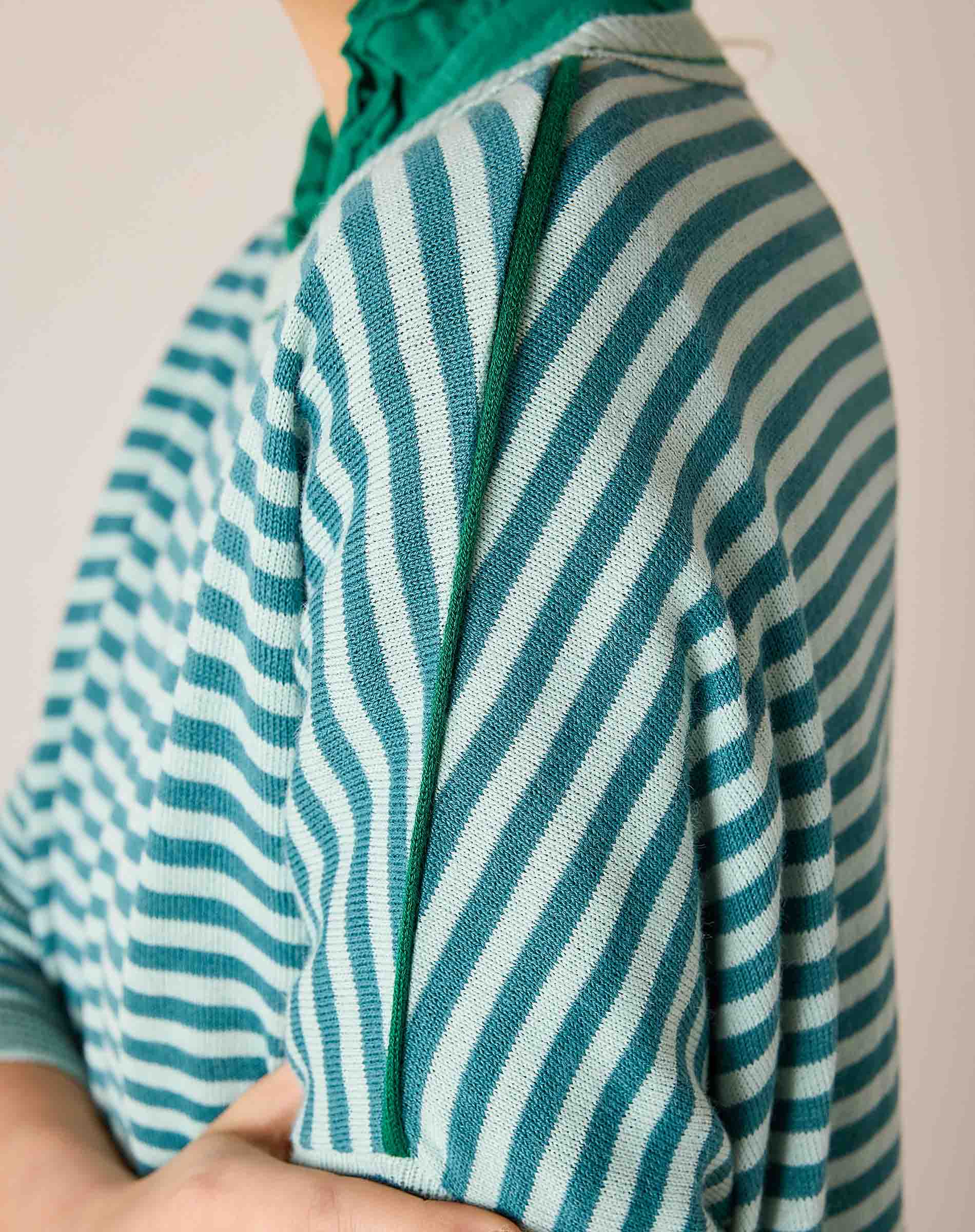 Close-up of a deep ocean rain green and white striped knit crewneck with a ribbed trim.
