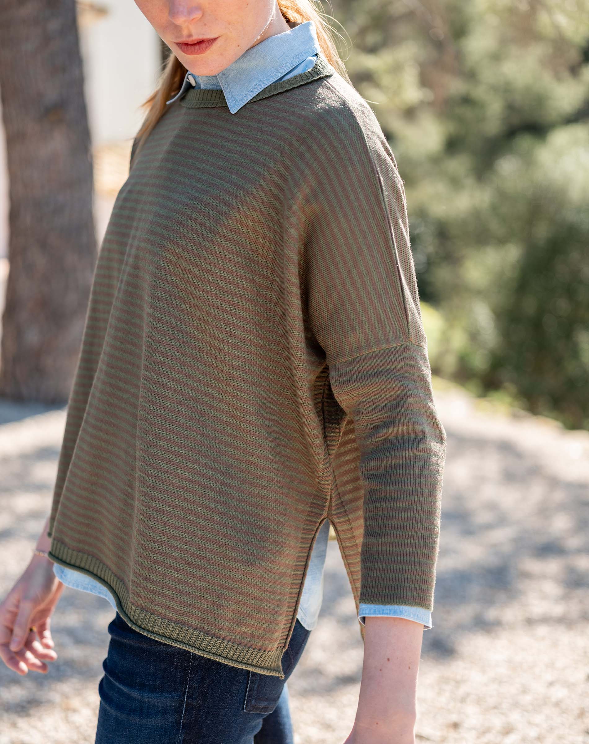 Tan and olive jungle stripe knit crewneck top worn over a light blue button-down shirt.