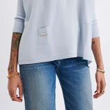 Light blue sweater and blue jeans worn by a person on a white background