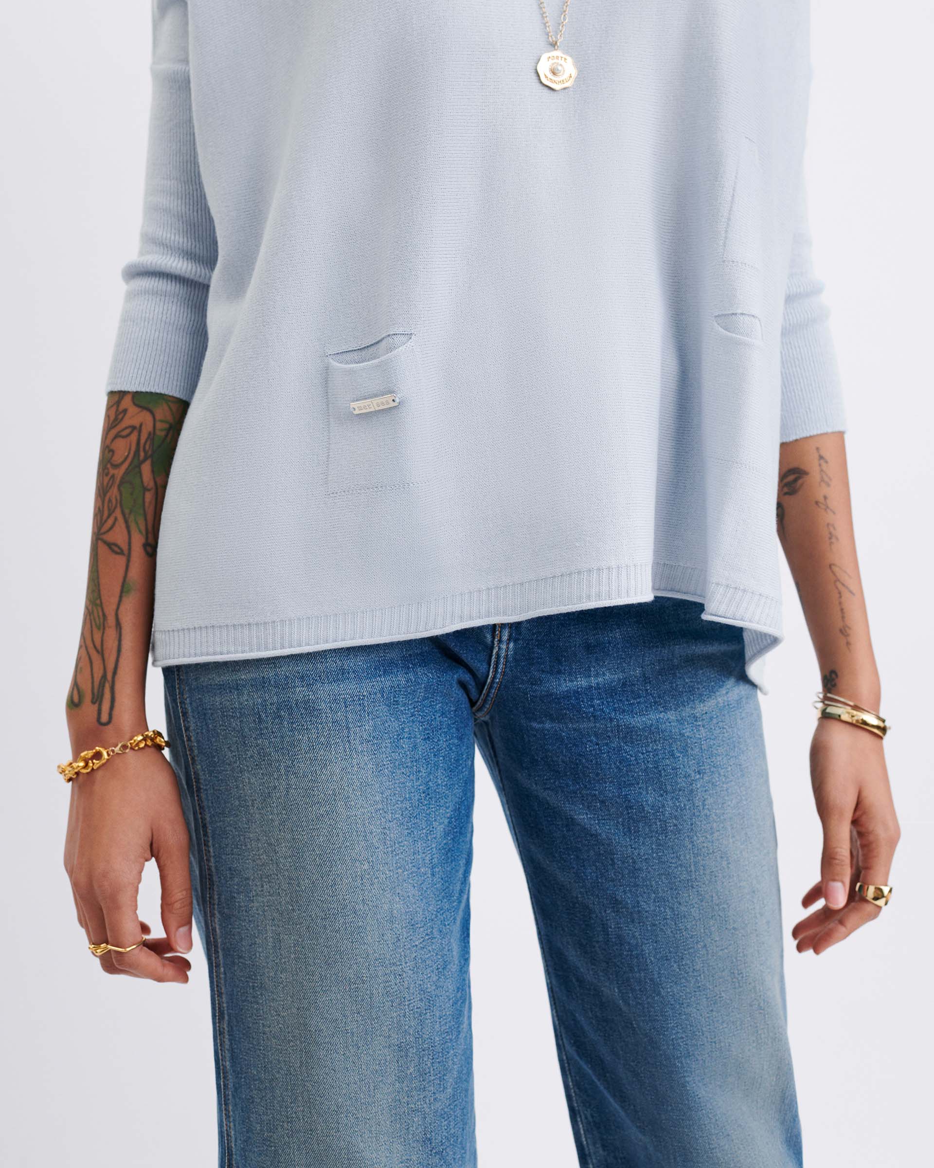 Light blue sweater and blue jeans worn by a person on a white background
