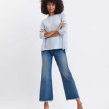 Woman wearing a light blue sweater and blue jeans on a white background