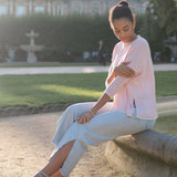 Woman sitting on a stone bench in a park with a castle in the background