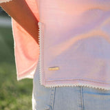 Close-up of a person wearing a light pink sweater with a blurred background