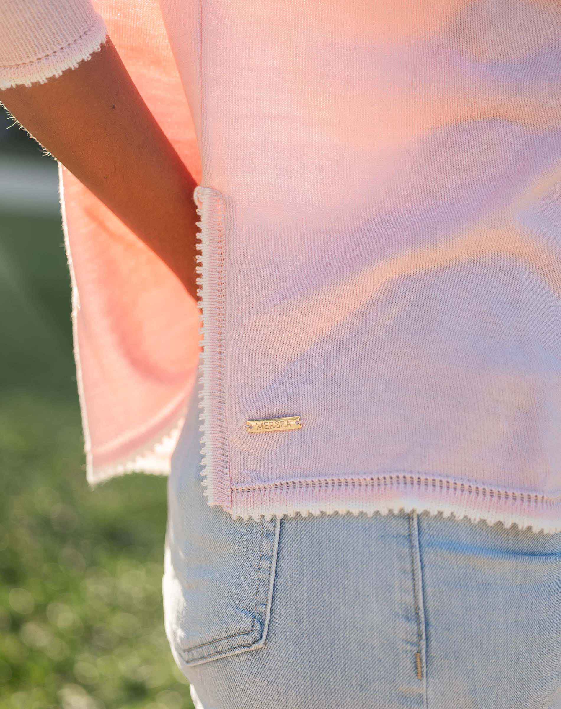 Close-up of a person wearing a light pink sweater with a blurred background