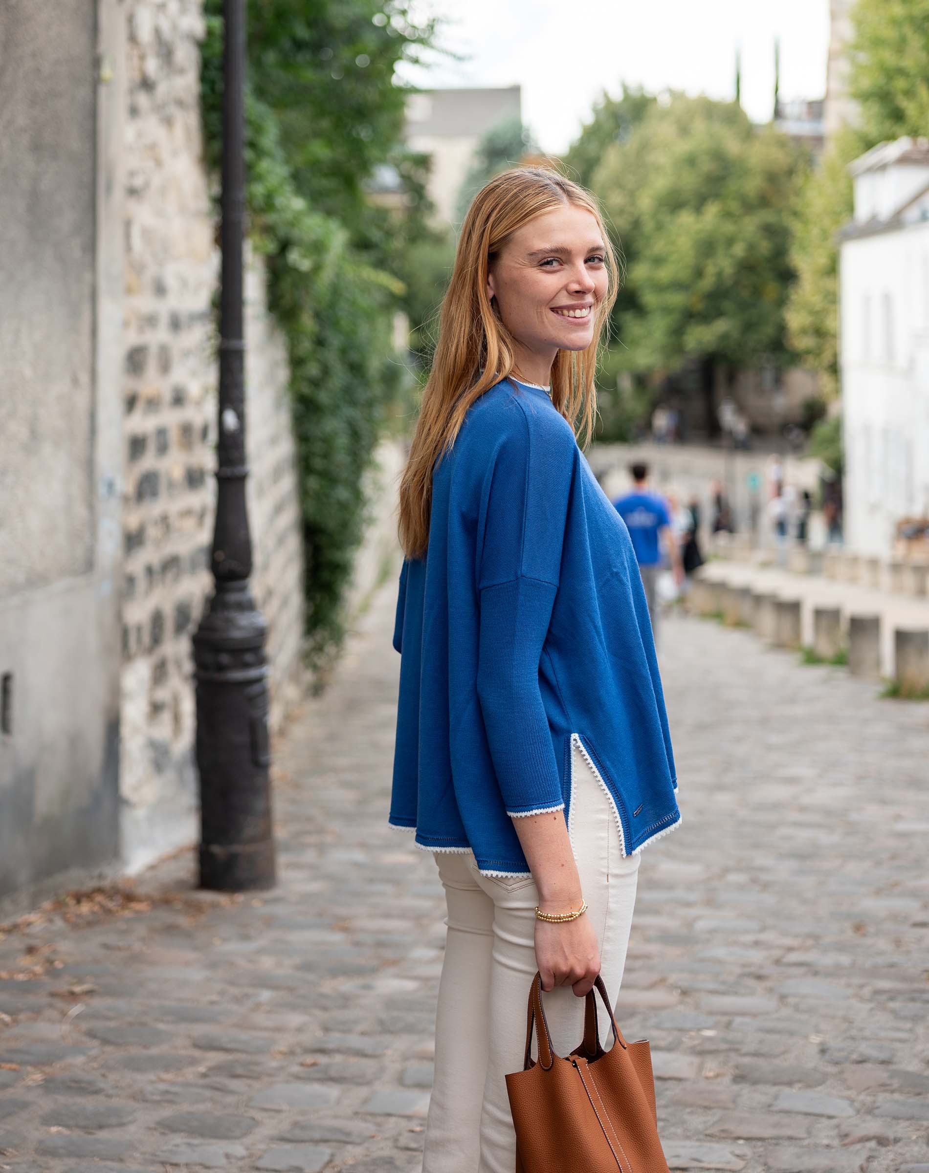 Woman in a blue jacket walking down a street
