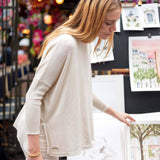 Woman in a white sweater looking at prints on a stand with a blurred background