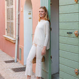 Woman in a white outfit standing in front of a colorful building with a green door.