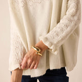 Cream-colored knit sweater featuring a pointelle stitch pattern and textured weave.