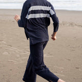 Person wearing a navy raincoat with white stripes on a beach