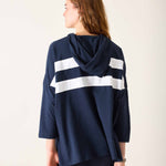 Person wearing a navy blue hoodie with white stripes from behind on a light background