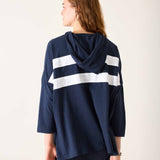 Person wearing a navy blue hoodie with white stripes from behind on a light background