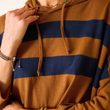 Close-up of a person wearing a brown and navy striped hoodie.