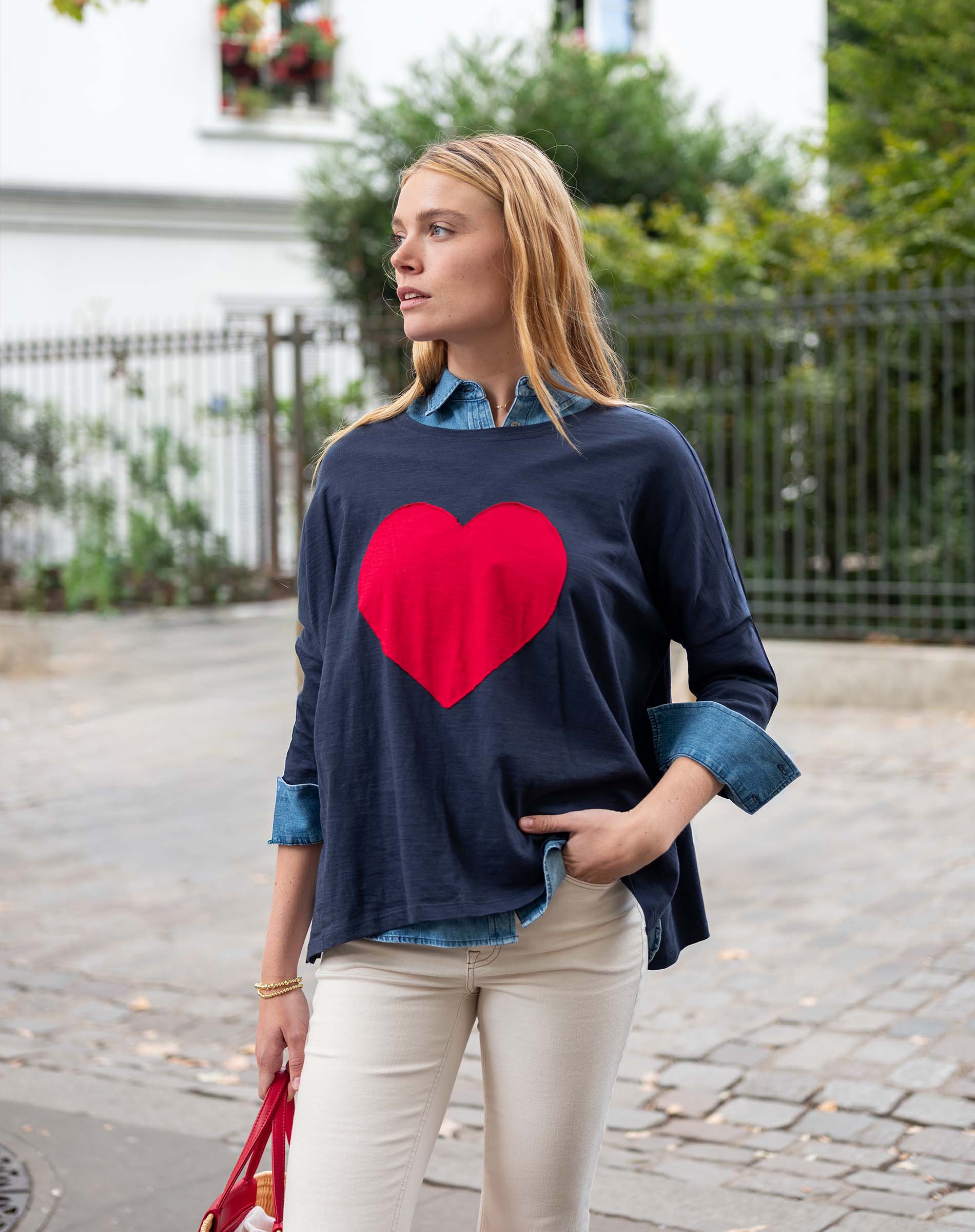 Woman wearing a navy sweater with a red heart design outdoors.