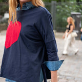 Person wearing a navy blue shirt with a red heart design and denim collar in an outdoor setting.