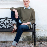 MERSEA women's travel-friendly olive green ribbed knit top over a light blue shirt with dark denim jeans.