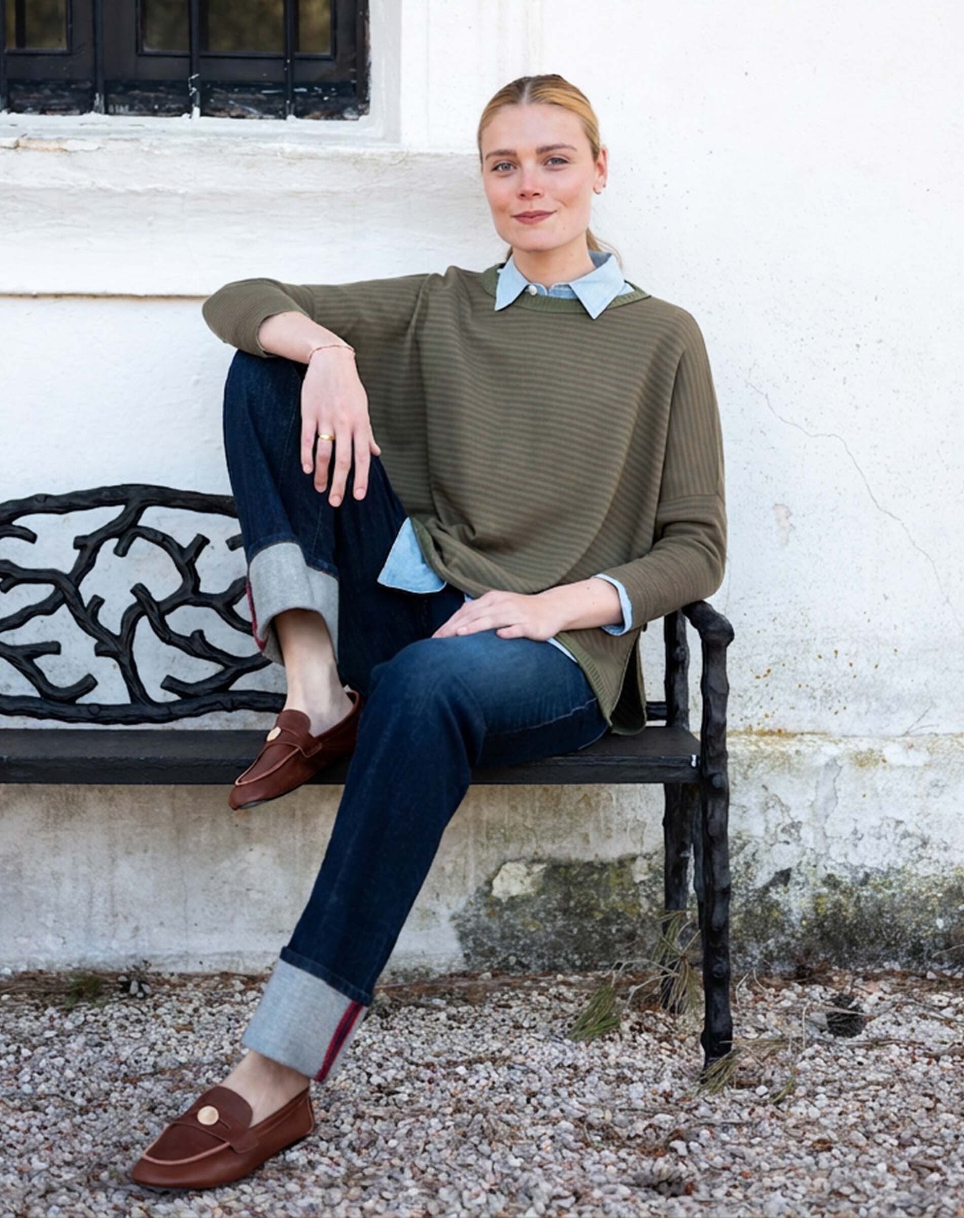 MERSEA women's travel-friendly olive green ribbed knit top over a light blue shirt with dark denim jeans.