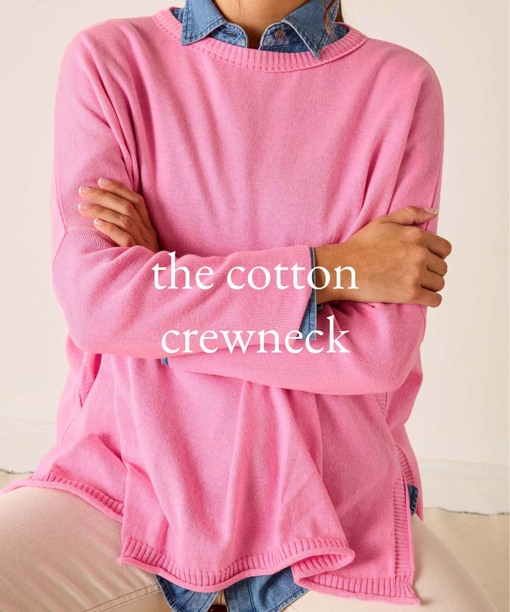 Person wearing a pink cotton crewneck sweater with denim collar and cuffs.