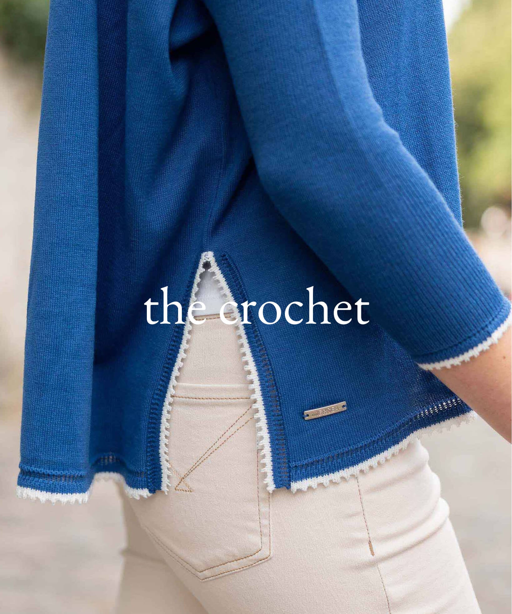 Blue crochet garment with white trim worn by a person, blurred background