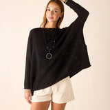 Woman wearing a black sweater and white shorts against a beige background