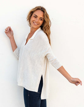 female wearing sea salt white polo sweater with split sides dancing on a white wall