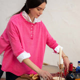 Fuchsia ruffle henley top with a buttoned placket and flared sleeves over a white shirt.