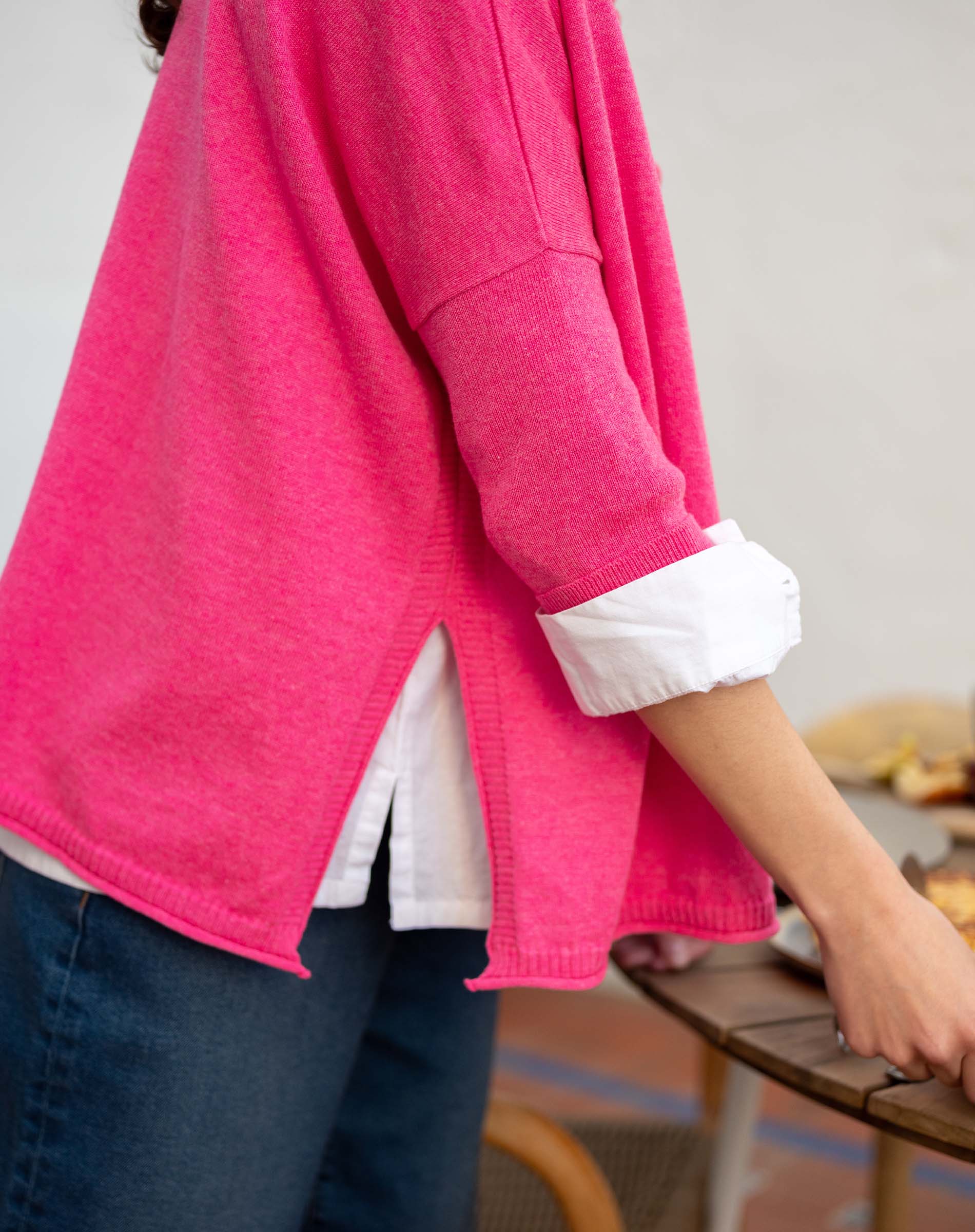 Fuchsia knit top with ruffled details and a layered white shirt underneath.