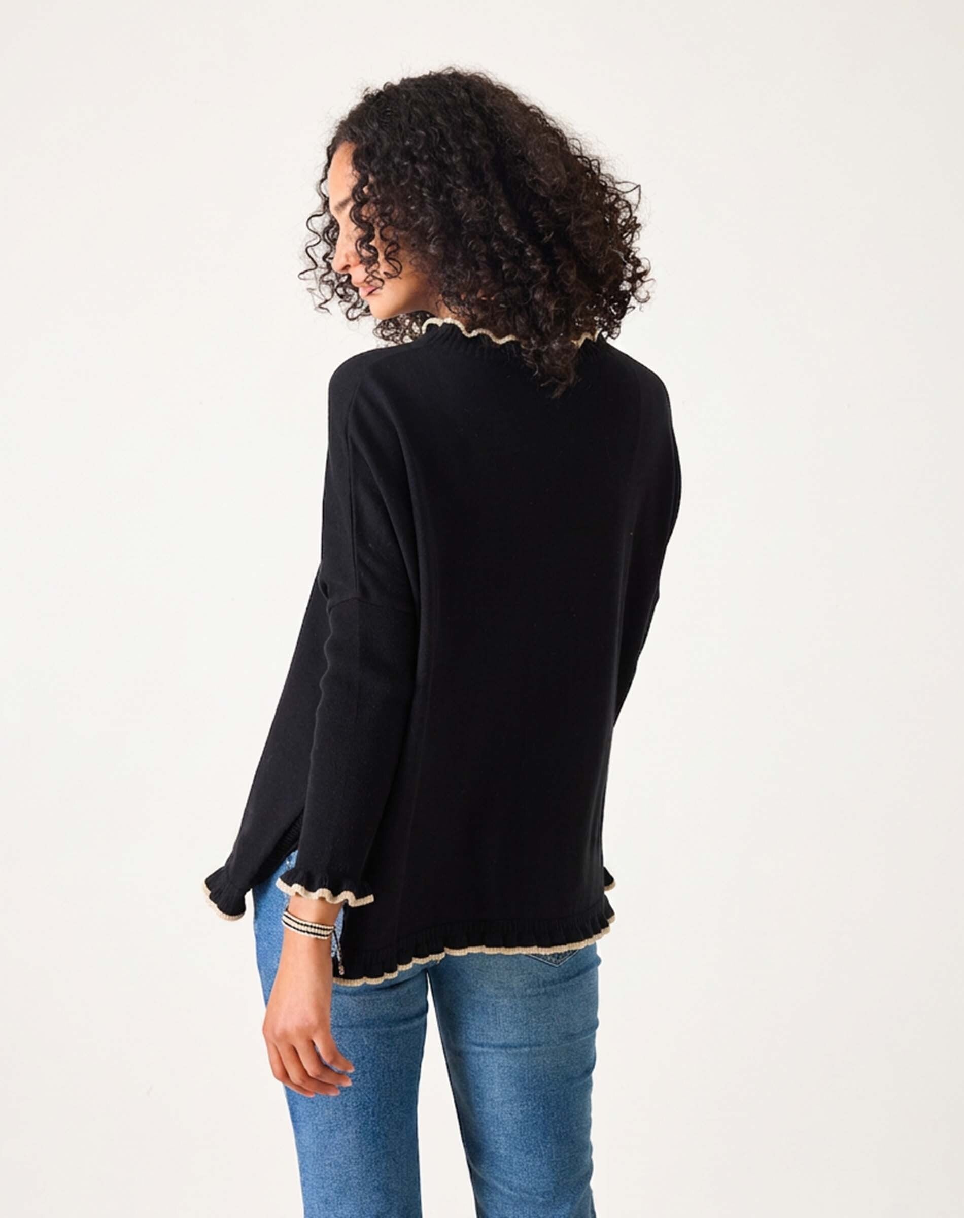 Back view of the black and taupe ruffled knit sweater with a scalloped hem over blue denim jeans.