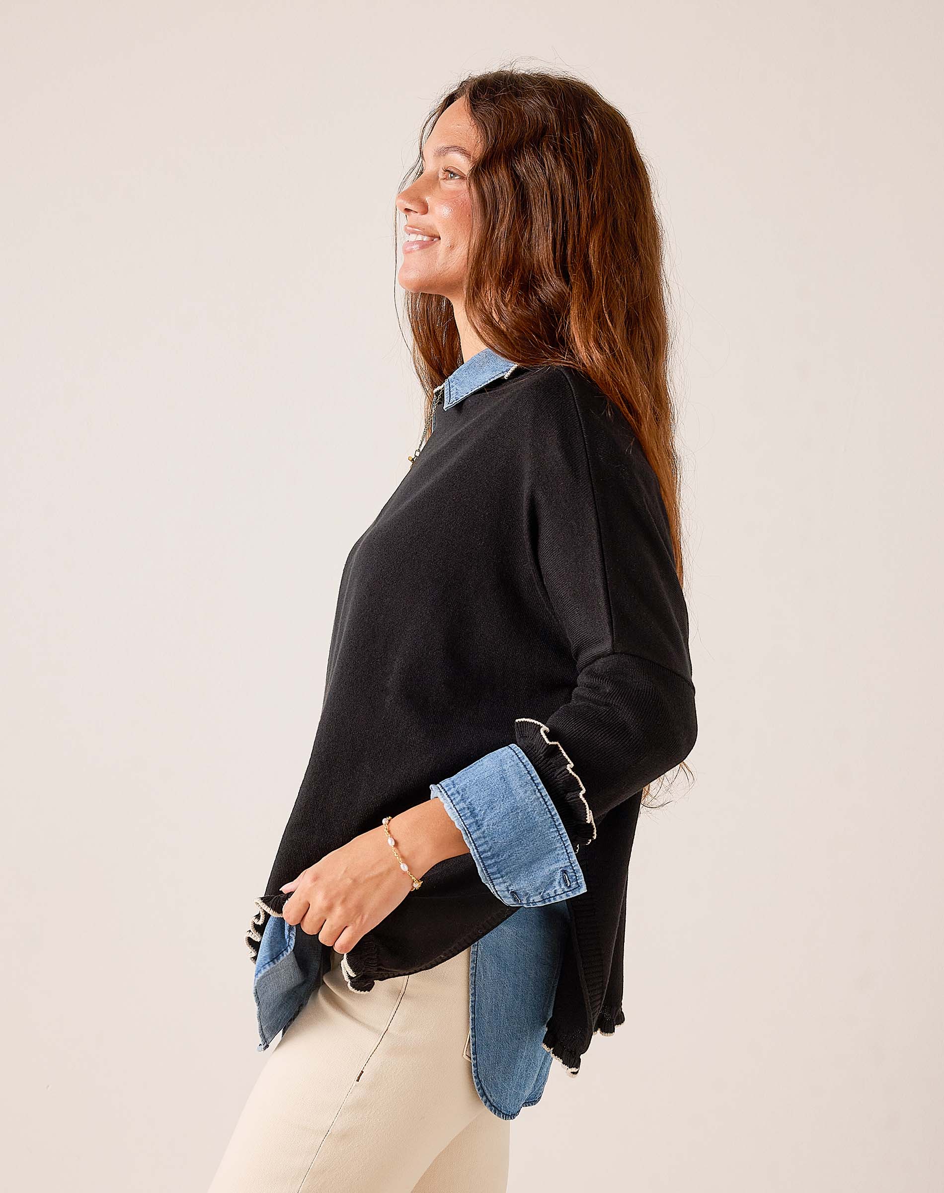 Black knit Catalina ruffle sweater with ruffled hem and contrasting blue denim-style layers.