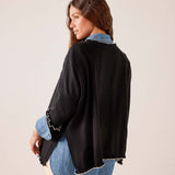Black oversized knit sweater with ruffled sleeve details and frayed hemline shown from the back view