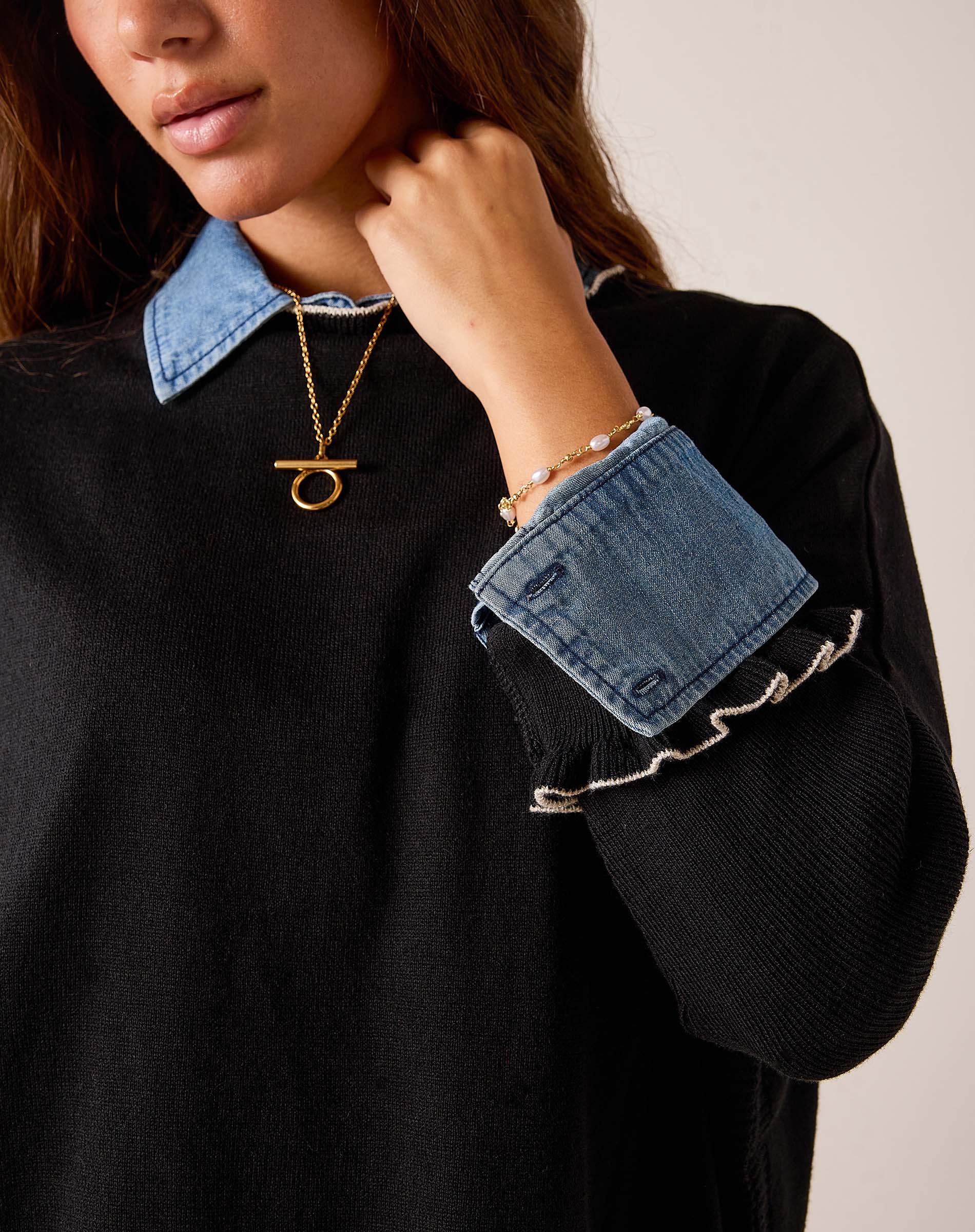 Black knit sweater with a denim-style collar and ruffled cuffs.