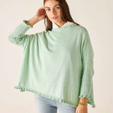 Woman wearing a light green poncho against a plain background