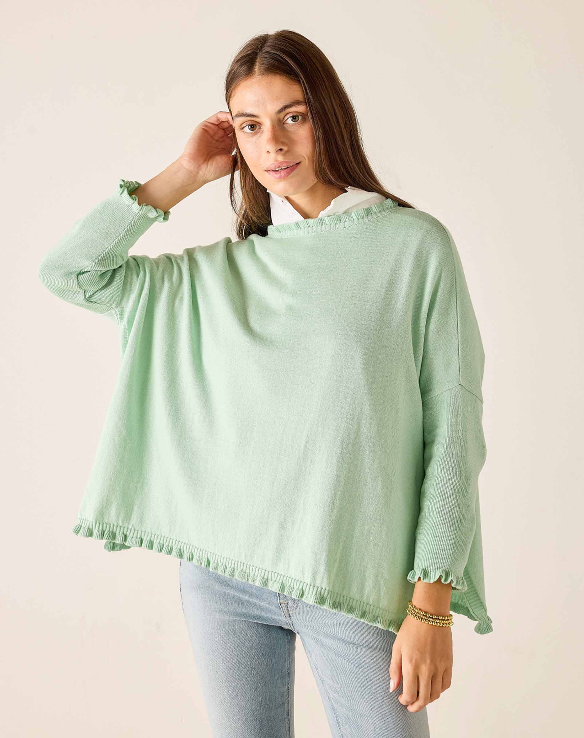 Woman wearing a light green poncho against a plain background