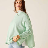 Woman wearing a light green sweater with a plain background