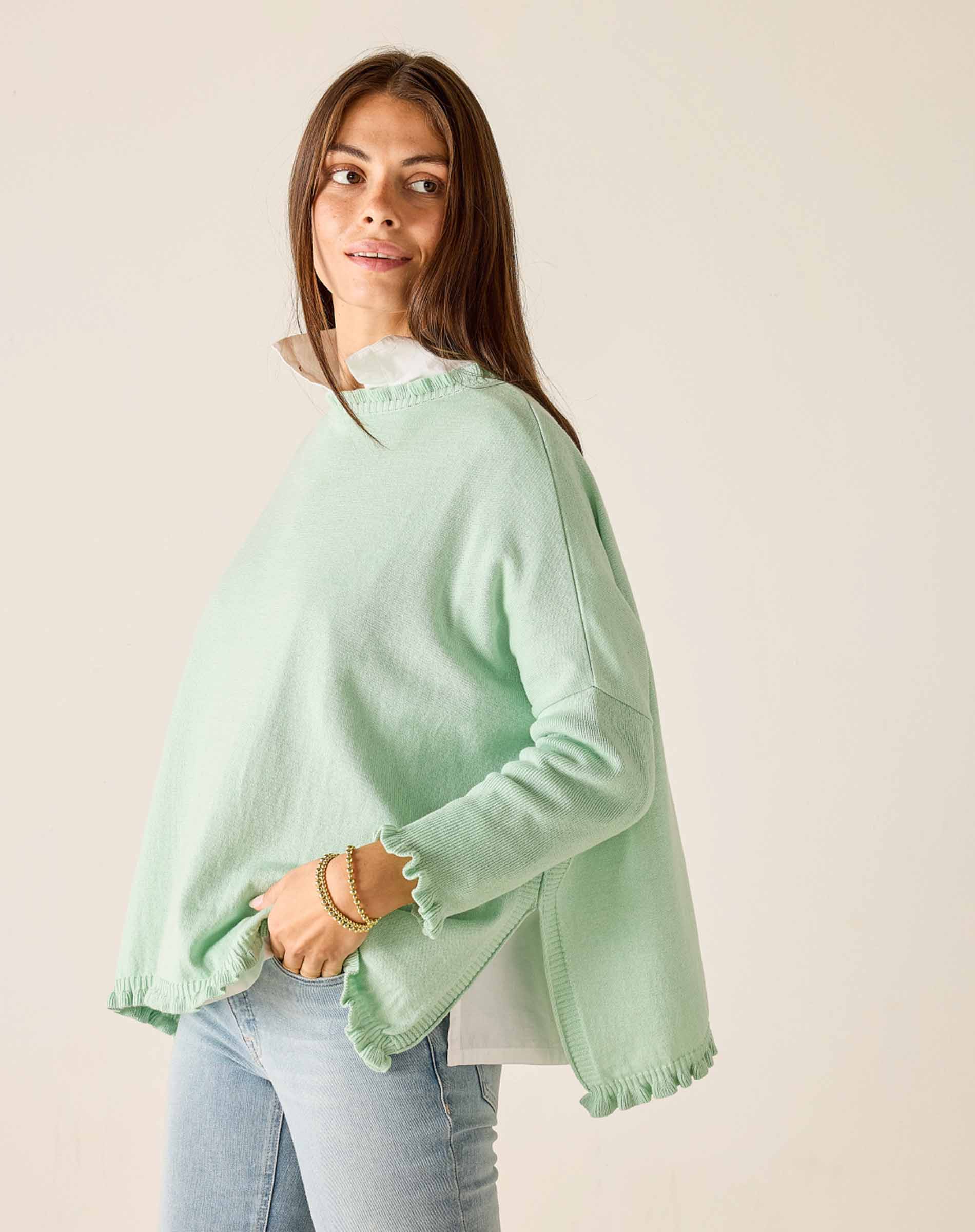 Woman wearing a light green sweater with a plain background