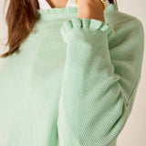 Close-up of a person wearing a light green sweater with a blurred background