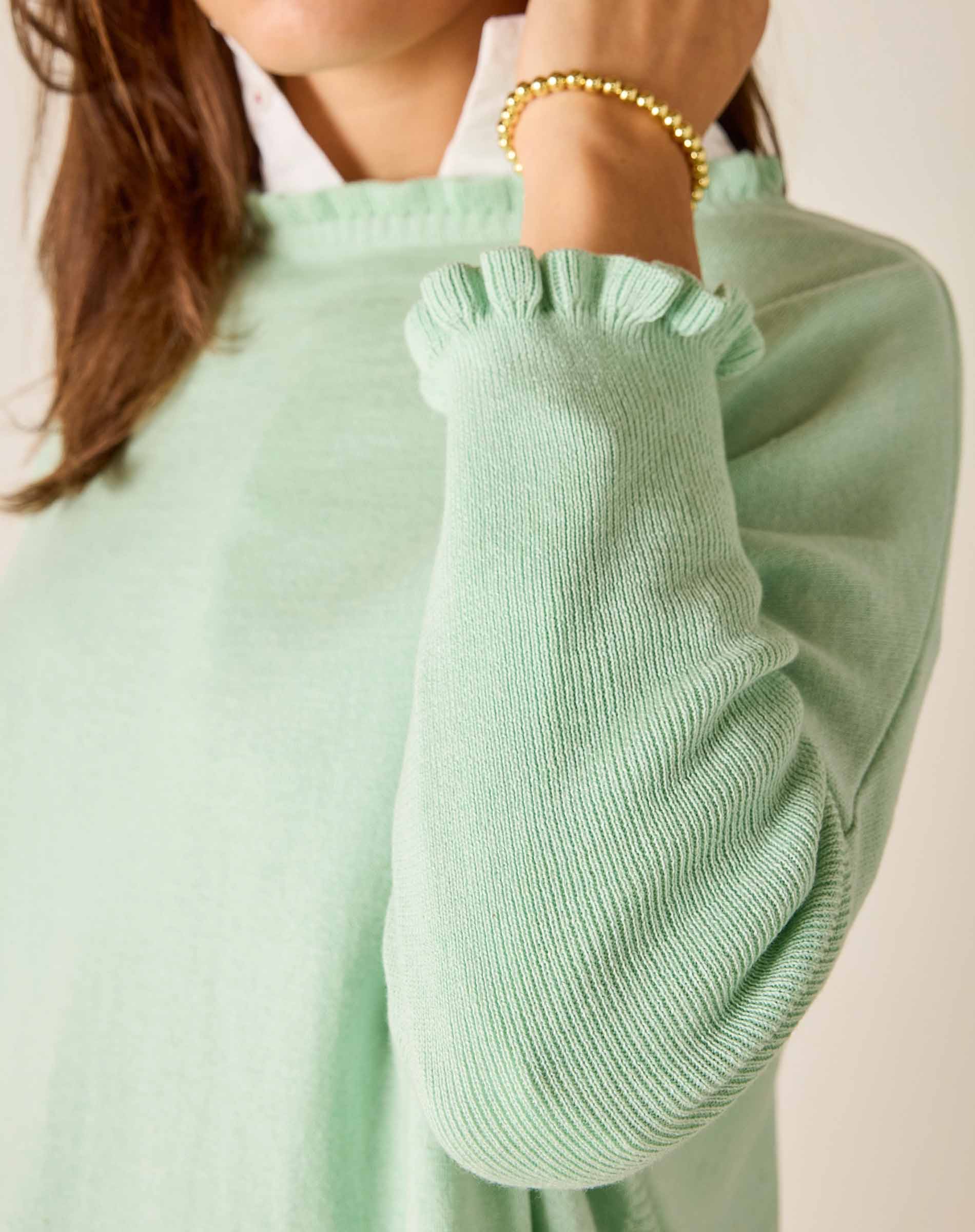 Close-up of a person wearing a light green sweater with a blurred background