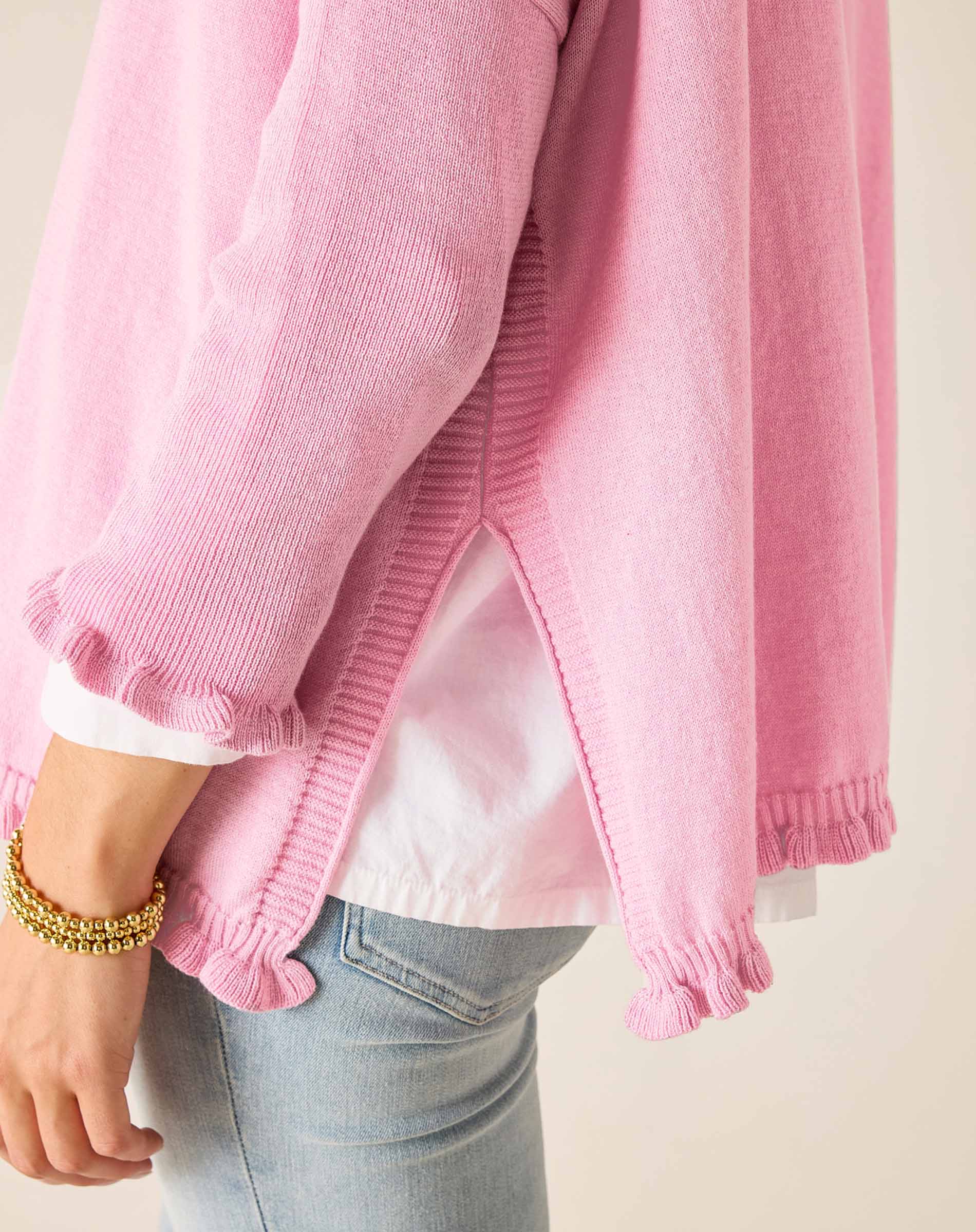 Pink cardigan over a white shirt with light blue jeans on a neutral background